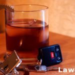 alcoholic drink sitting next to car keys and handcuffs on table