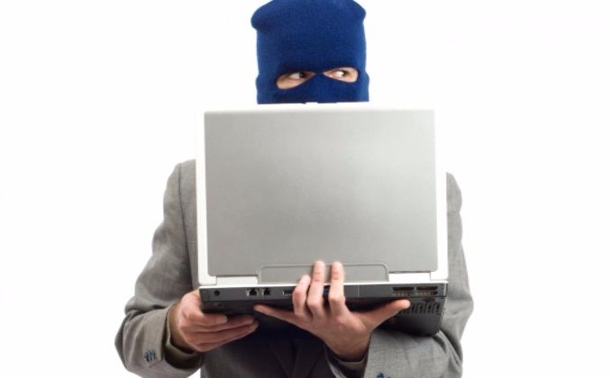 man with mask holding a computer and committing fraud