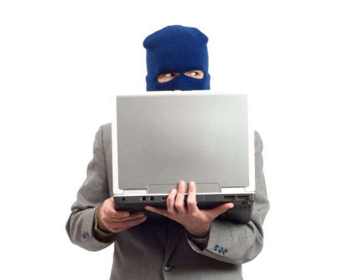 man with mask holding a computer and committing fraud