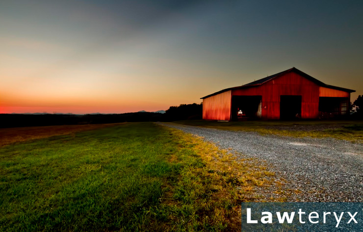 red barn sitting on farmland at sunset